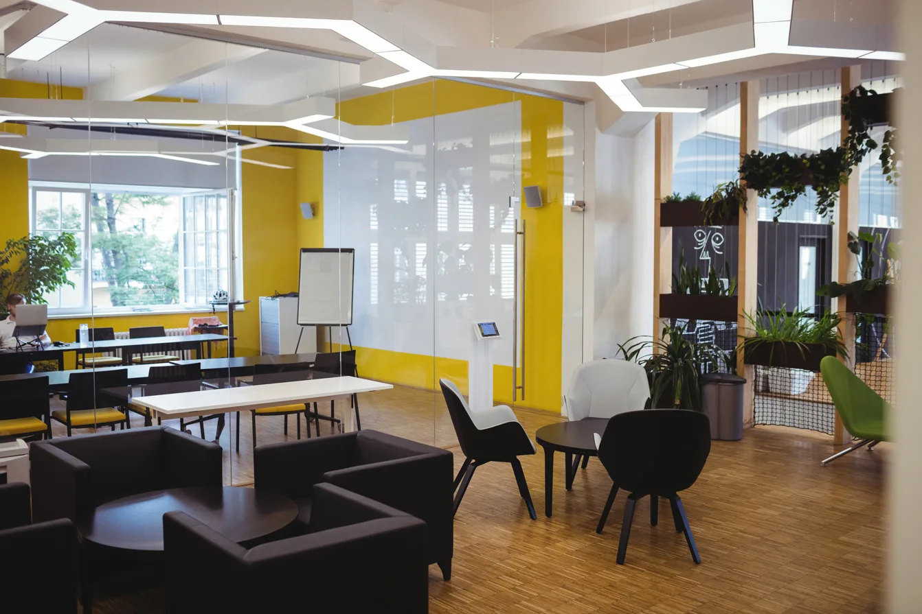 Modern office interior with vibrant yellow accent walls and multifunctional workspace.
